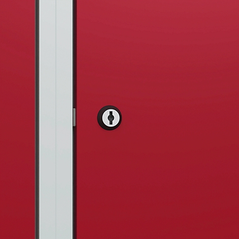 Détail d'une armoire rouge avec serrure et encadrement de porte blanc.