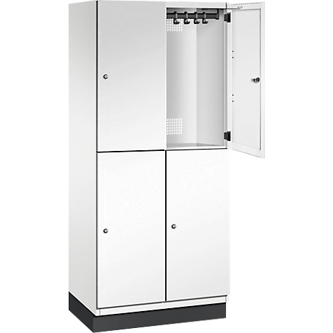 Armoire blanche avec quatre portes, dont une ouverte. Barre de crochets et fentes d'aération visibles.