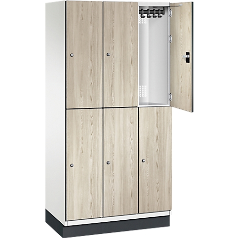 Un casier avec la porte ouverte. L'armoire est décorée de bois clair et repose sur un socle noir.