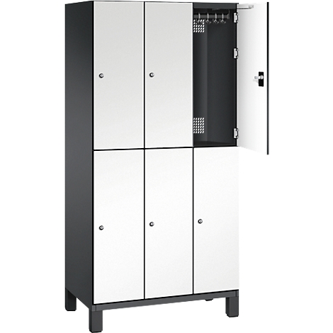 Une armoire à six compartiments, dont trois sont ouverts. Portes blanches, corps sombre, avec une tringle à vêtements en métal dans le compartiment ouvert.