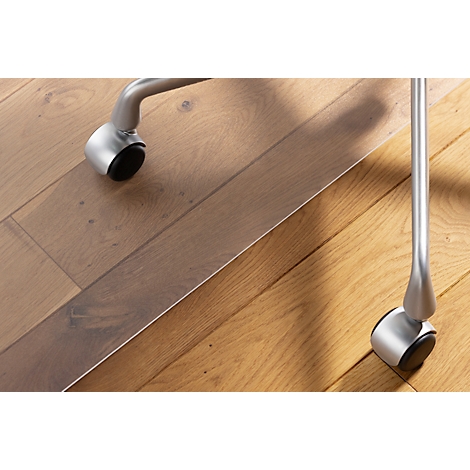 Detailopname: stoelpot met wiel op een houten vloer. Op de voorgrond een transparante vloerbeschermingsmat.