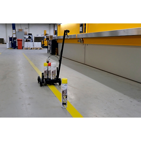 Gele lijn op betonnen vloer met markeerwagen en spuitbus.