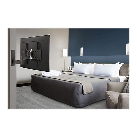 Ein Fernseher hängt an einer Halterung über einem Bett. Das Zimmer ist modern eingerichtet, mit Sofa und Nachttisch.