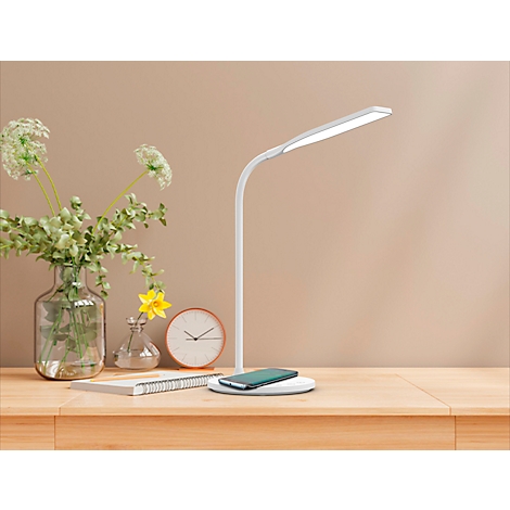 Bureau met lamp, telefoon en bloemen. De witte lamp brandt. Op het bureau liggen een telefoon, een klok en een notitieblok.