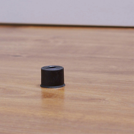 Schwarzer Zylinder auf Holz. Der Zylinder hat eine runde Öffnung in der Mitte.