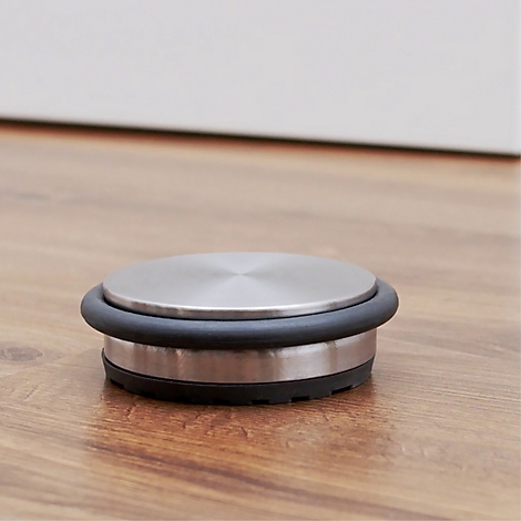 Ronde metalen deurstopper met zwarte rubberen ring op houten vloer.