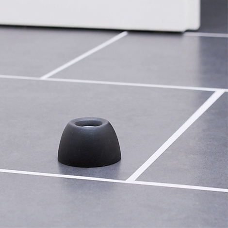 Een zwart oordopje ligt op een grijs betegeld oppervlak. Witte lijnen vormen een rasterpatroon.