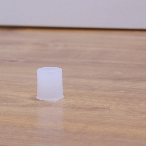Een witte, cilindervormige plastic plug staat op een houten oppervlak.