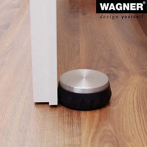 Een deurstopper met een roestvrijstalen oppervlak en zwarte rubberen ring staat voor een deur. Op de houten vloer staat een logo.