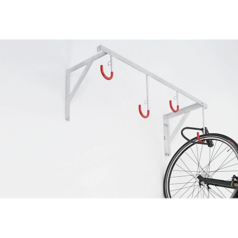 Bike rack with red hangers on the wall. A bike tire hangs in the rack.