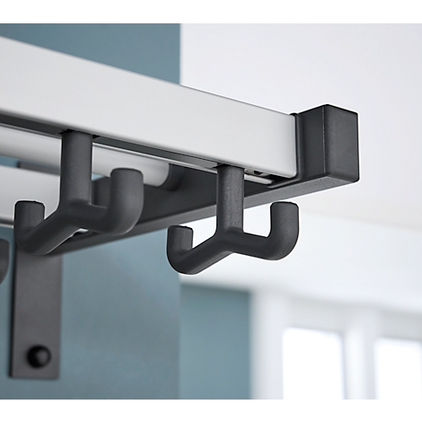 Detailaufnahme einer Garderobe: Graue Haken an einer weißen Stange, an einer blauen Wand.