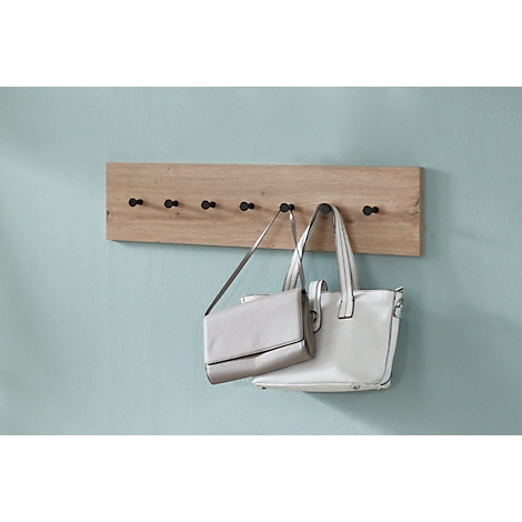 Garderobenleiste aus Holz mit schwarzen Haken, an denen zwei Handtaschen hängen.