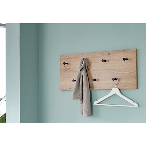 Holzgarderobe an hellblauer Wand. Ein grauer Schal hängt an der Garderobe. Darunter ein weißer Kleiderbügel.