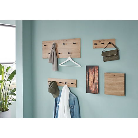 Hölzerne Wandgarderobe mit Kleidung und Accessoires an einer hellblauen Wand.