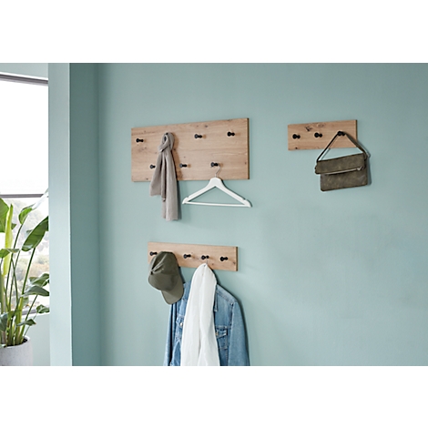 Holzgarderobe mit Kleidung und Accessoires an hellblauer Wand.