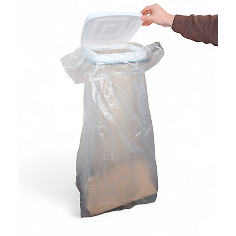 Eine Hand öffnet den Deckel eines weißen Mülleimers mit einer transparenten Plastiktüte.
