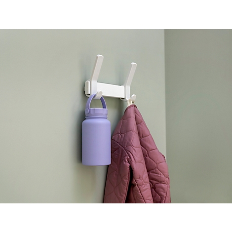Witte haak aan een muur bevestigd met paarse waterfles en roze jas.