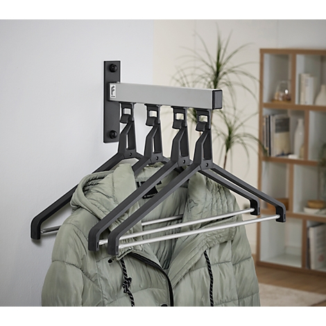 Wandgarderobe met grijze kleerhangers, met een jas die eraan hangt. Op de achtergrond is een plank zichtbaar.