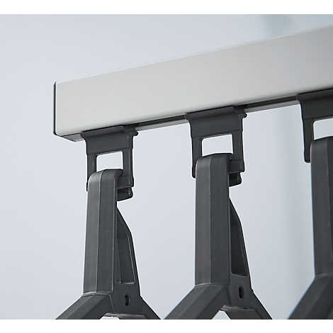 Close-up van een grijze kledingrail met hangende kleerhangers.