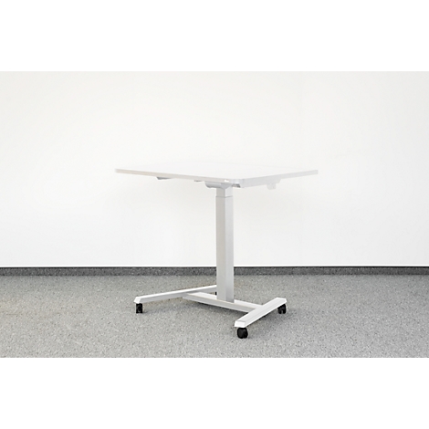 In hoogte verstelbaar grijs bureau tegen witte muur. Hij staat op wielen.