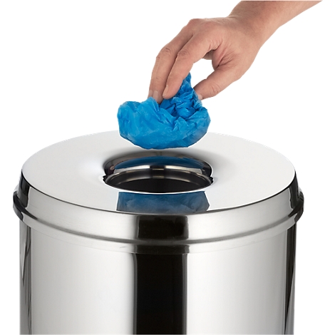 Hand throwing a blue trash bag into a stainless steel trash can.