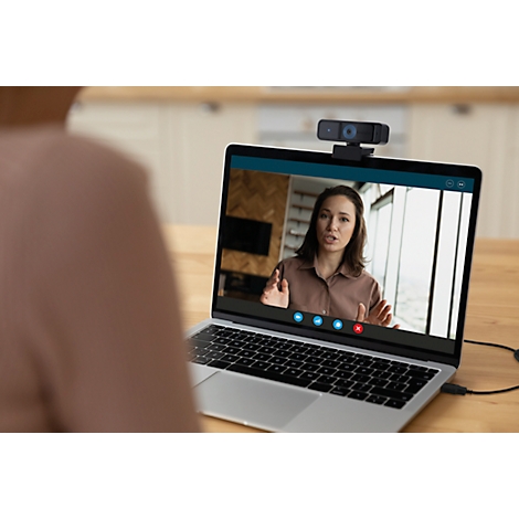 Personne devant un ordinateur portable, en visioconférence avec une femme. Webcam sur l'écran, câble connecté.
