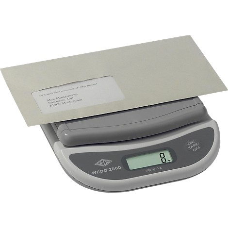 An envelope rests on a gray scale, which displays 8 grams. The envelope has a window and address information.