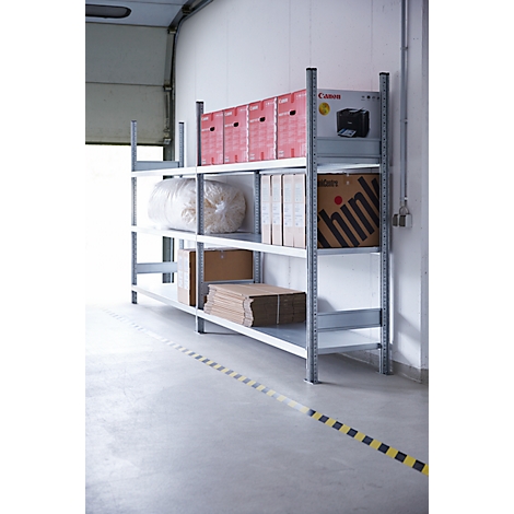 Metallregal mit Kisten, Kartons und einem Drucker. Im Vordergrund ein schwarz-gelbes Warnband.