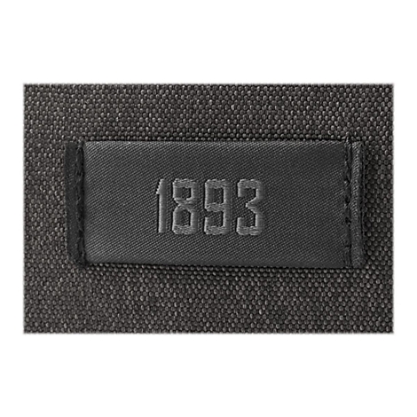 Detailaufnahme eines dunkelgrauen Textilstücks mit dem aufgestickten Jahr „1893“ auf einem eingenähten Etikett.