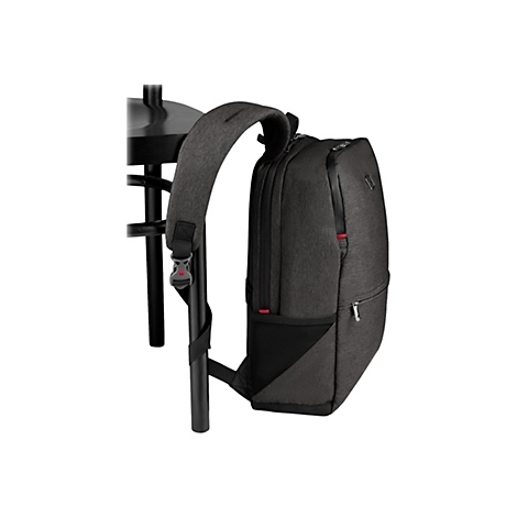 Dunkelgrauer Rucksack, an einer schwarzen Stuhllehne befestigt. Details: Reißverschlüsse, rote Akzente, Textur.