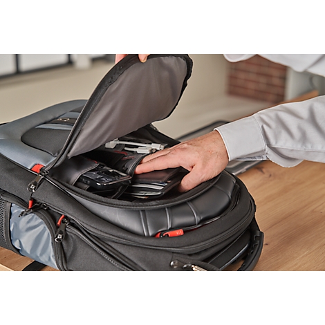 Une personne ouvre un sac à dos noir rempli d'appareils électroniques.