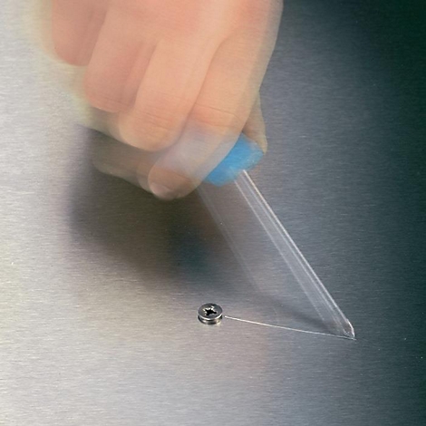 Main floue avec un tournevis fixant une vis sur une surface métallique.