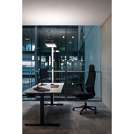 Een modern kantoor met een bureau, bureaustoel, lamp en uitzicht door een glazen gevel.