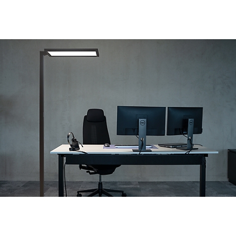 Kantoor met bureau, monitoren, stoel en staande lamp. Neutrale achtergrond.