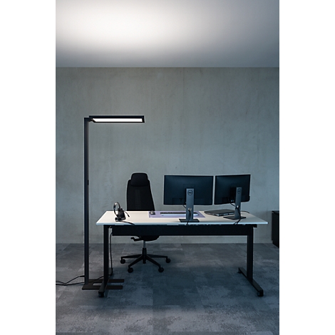 Kantoor met bureau, monitoren, vloerlamp en bureaustoel.