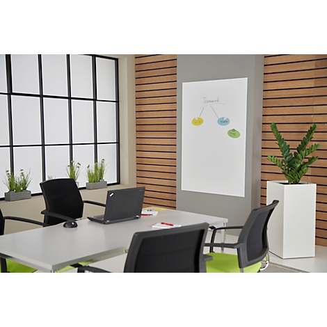 Conference room with table, chairs, and flipchart. Window in background. Colorful graphic on whiteboard.