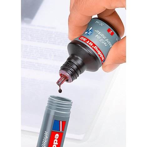 Een hand vult een Edding whiteboard marker met rode inkt. De inktfles, de marker en een vel papier zijn zichtbaar.