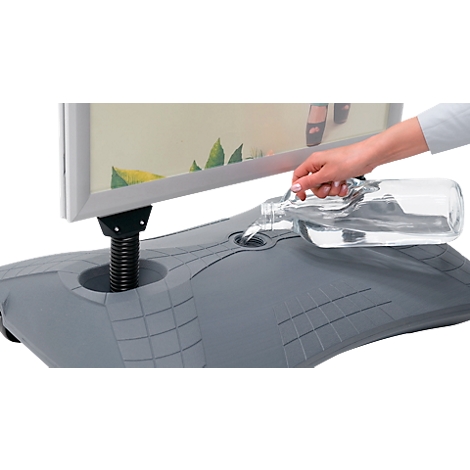 Een hand giet water in een standaard. De standaard houdt een reclamebord vast.