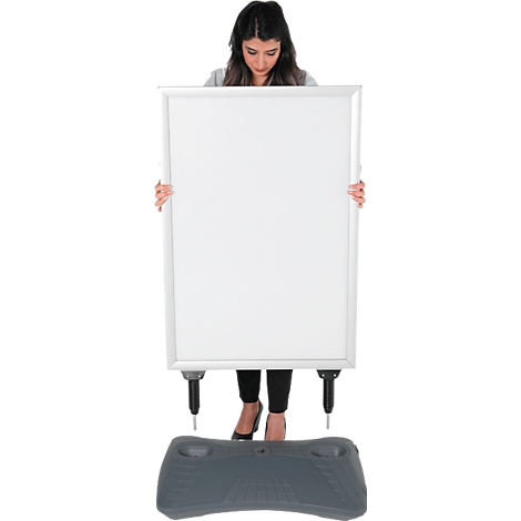 Une femme tient un grand tableau blanc vierge. Une base grise est au sol.