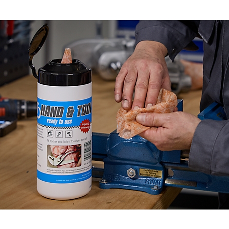 Ein Mann reinigt mit einem Feuchttuch einen Schraubstock. Daneben steht eine Dose mit Reinigungstüchern.