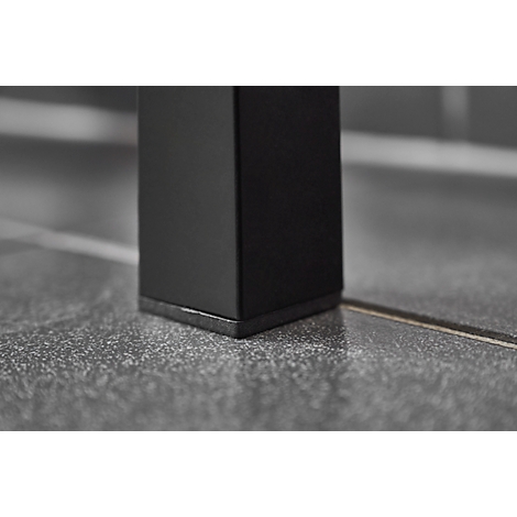 Close-up of a black table leg corner on a gray tiled floor.