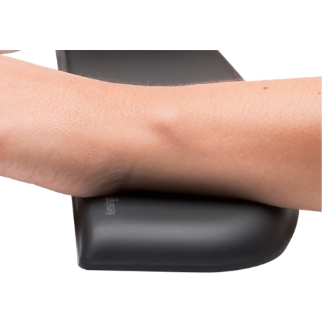 Arm resting on a black wrist rest. Pillow with the inscription: Kensington.