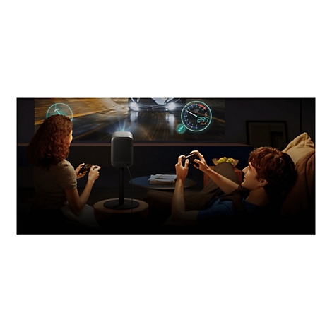 Ein junges Paar spielt Videospiele, die ein kompakter Beamer auf die Wand projiziert.