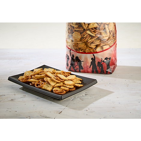 Des collations sur une assiette carrée noire, à côté d'un sac plein de crackers. Le sac montre des silhouettes dansantes.