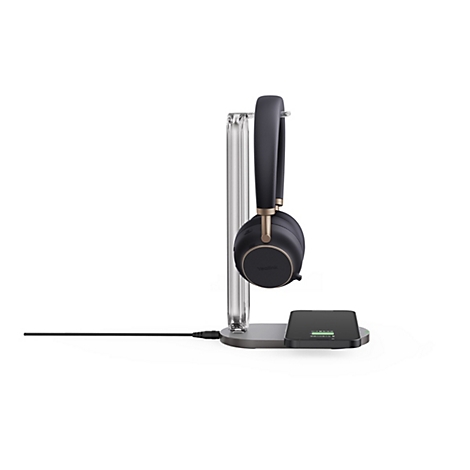 Casque sans fil noir et or sur un chargeur. Un smartphone avec un indicateur de charge est visible sur le chargeur.