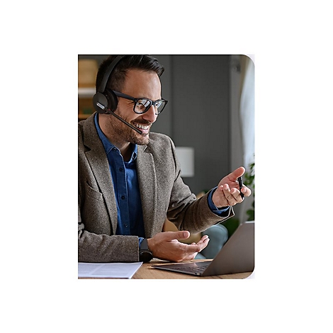 Ein Mann mit Brille und Headset, lÃ¤chelnd wÃ¤hrend eines Videoanrufs an einem Laptop. Er gestikuliert mit der Hand.