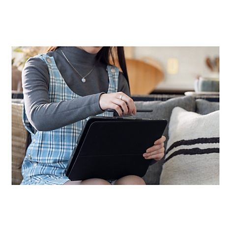 Eine Person hält ein schwarzes Tablet, daneben ein Stift. Sie trägt ein blau-weiß kariertes Kleid.