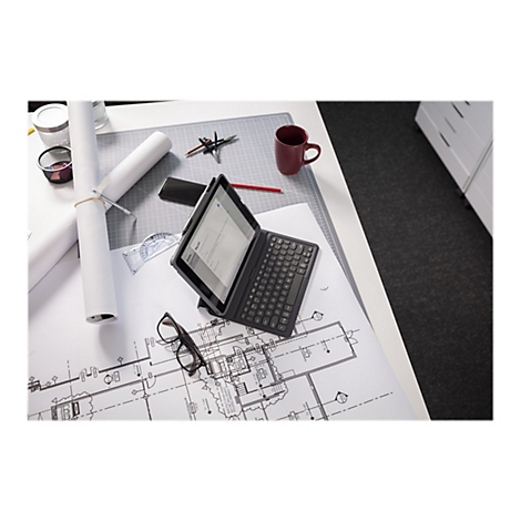 Draufsicht auf einen Schreibtisch mit einem Tablet mit Tastatur, Bleistift, Brille, BauplÃ¤nen und einer Kaffeetasse.