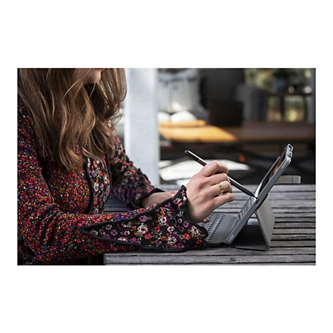 Personne écrivant sur une tablette avec un stylo. Elle porte une bague. Ses vêtements ont un motif floral.