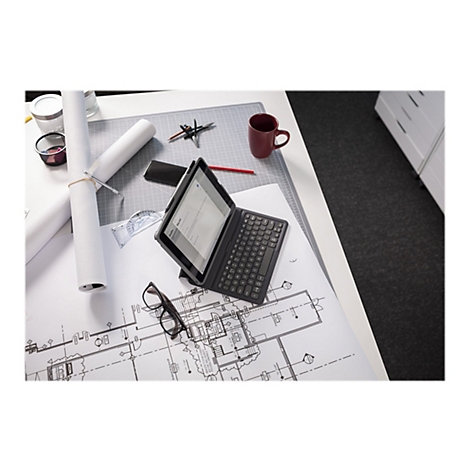 Ein Tablet mit Tastatur liegt auf einem Tisch mit Bauplänen, Zeichenutensilien und einer Kaffeetasse. Auf dem Bildschirm ist ein Dokument zu sehen.